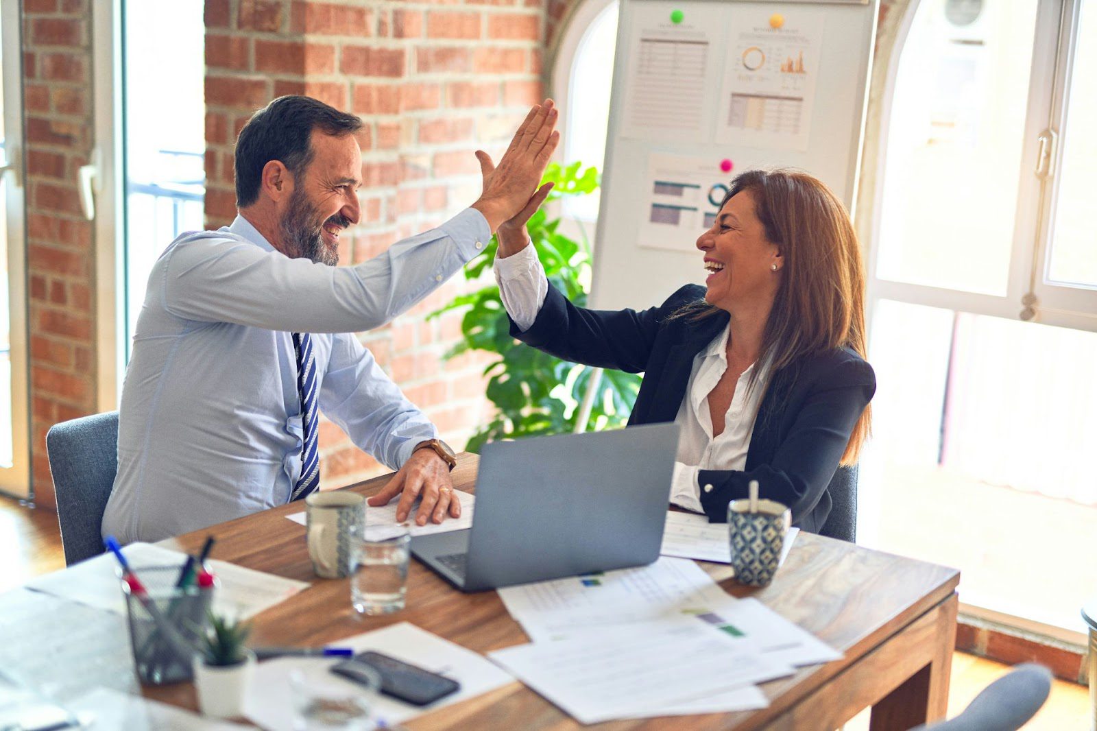 A man and a woman high-fiving in a workplace